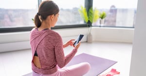 Woman working out at home using preventive health program on phone