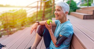 Senior woman eating an apple after her run outside