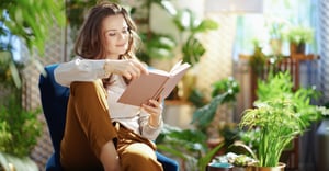 Woman reading a book surrounded by plants