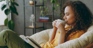 Woman drinking coffee reading on couch