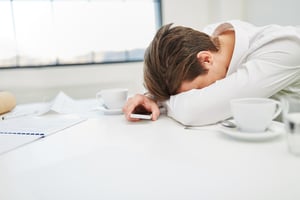 Guy with his head on his desk, burned out from work