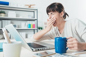 Tired woman working at her computer with coffee