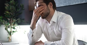 Employee man stressed in office at work with hand over face
