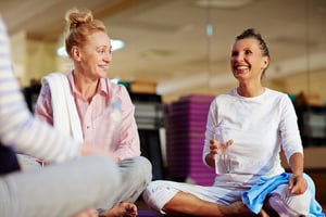 Two woman working out together sitting down resting